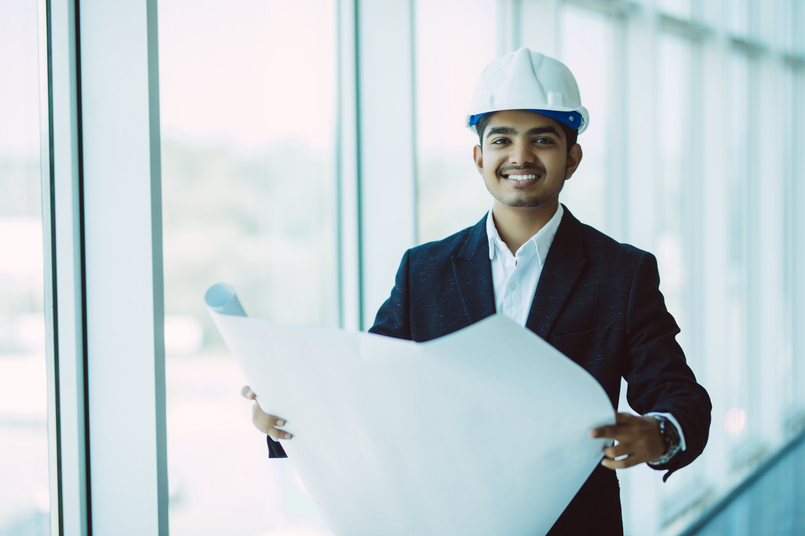 indian architect or engineer at work on a building site. checking plans against the construction work.
